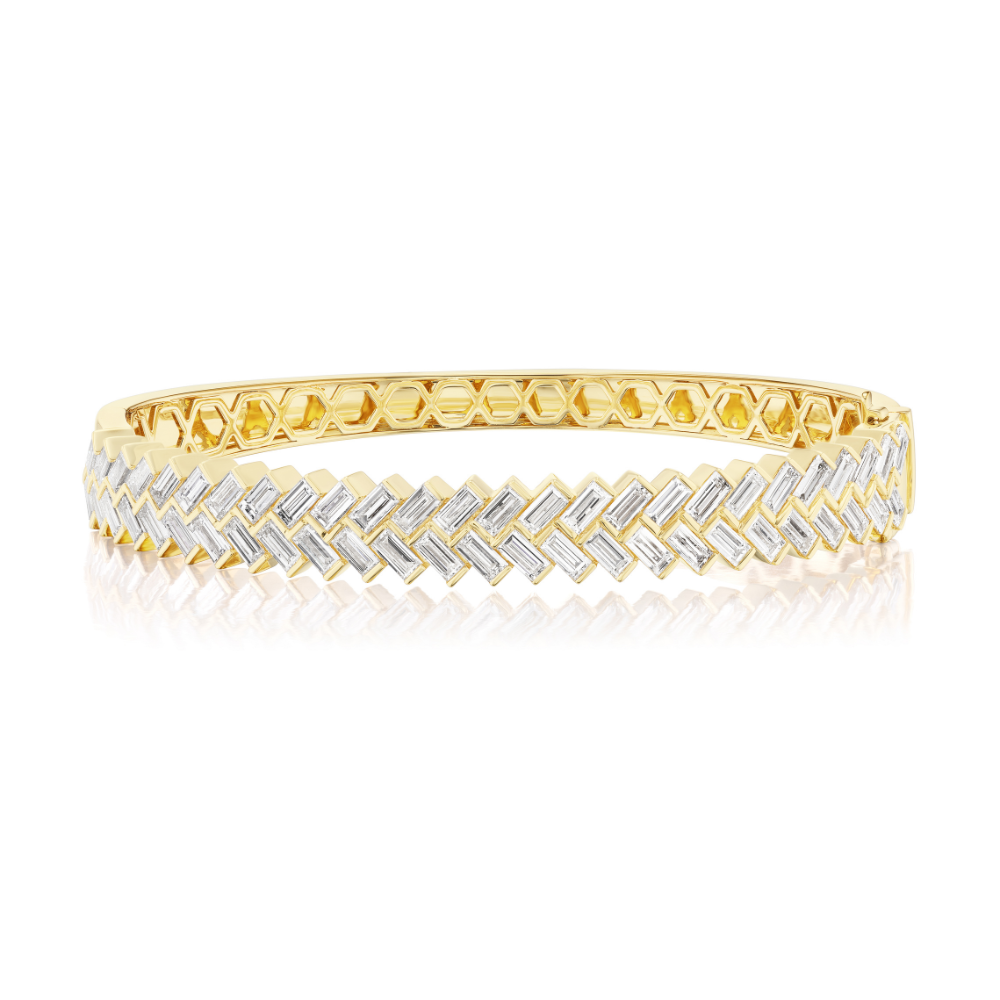 Yellow gold hinged bangle bracelet with baguette-cut diamonds arranged in a herringbone pattern across the top of the bangle.