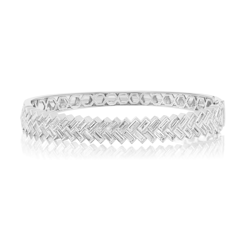 White gold hinged bangle bracelet with baguette-cut diamonds arranged in a herringbone pattern across the top of the bangle.